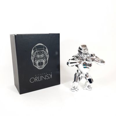 the silver figurine is next to a black box with a logo on it