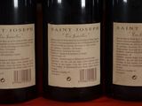 three bottles of wine are lined up on a shelf