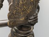 bronze statue of a woman holding a fan in her hands