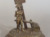 figurine en bronze représentant un homme tenant une pancarte et accompagné d'un chien