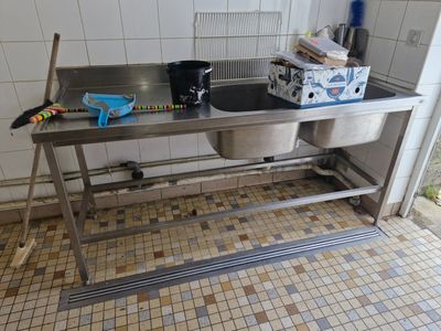 une cuisine équipée d'un évier et d'une poubelle posée sur le plan de travail