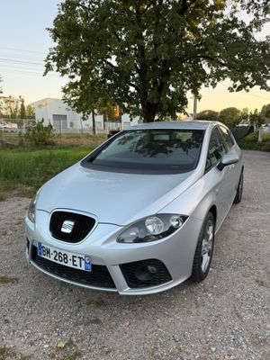 La voiture est garée sur le gravier, près d'un arbre.