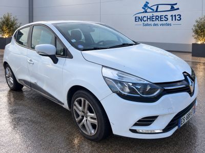 Une voiture blanche est garée devant un immeuble.