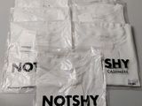 quatre sacs de t-shirts blancs posés sur une table