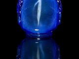 blue glass snuff bottle sitting on a reflective surface with a black background