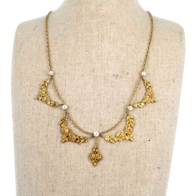 un collier en or orné de feuilles et de perles sur un mannequin