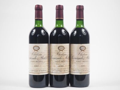 trois bouteilles de vin rouge posées l'une à côté de l'autre sur une surface blanche