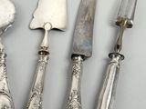 four silver plated knives and a knife on a white surface