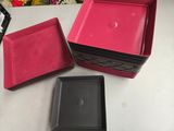 trois plateaux carrés roses et noirs posés sur une table blanche