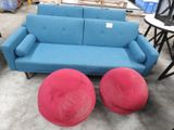 un canapé bleu et deux tabourets rouges dans un entrepôt