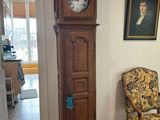 a grandfather clock in the corner of a room next to a chair