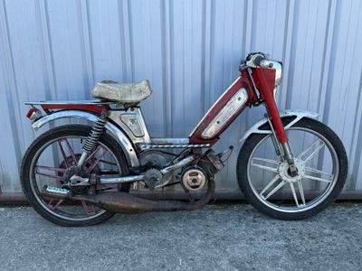 une moto rouge et argentée garée à côté d'un immeuble