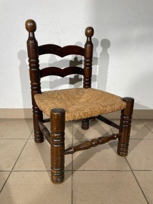 a wooden chair with a woven seat on a tile floor