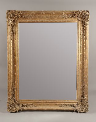 un grand miroir dans un cadre doré, orné d'un motif décoratif
