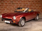 an image of a red sports car parked in front of a brick wall