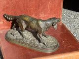 une statue représentant un chien dans une valise, posée par terre
