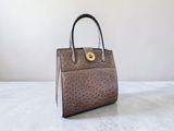 un sac à main en autruche marron posé sur une table blanche