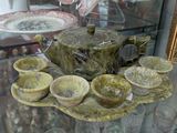 a tea pot and cups on a tray in a glass case