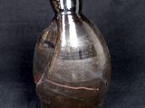 a silver vase that is sitting on a black surface