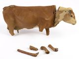une vache qui se tient à côté de quelques morceaux de bois