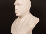 white marble bust of a man on a wooden table against a black background