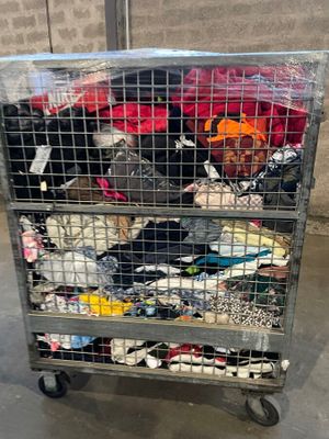 a metal cart filled with lots of clothes in a warehouse