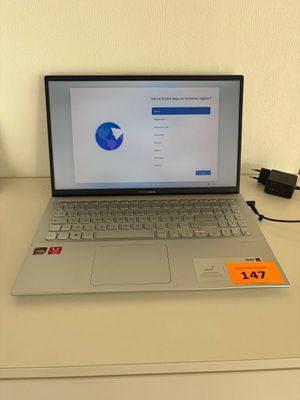 un ordinateur portable posé sur un bureau, avec son chargeur branché dessus