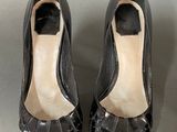 pair of black shoes with a black heel on a gray surface