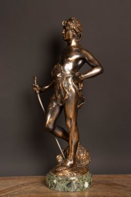 a bronze statue of a woman holding a sword on top of a wooden table