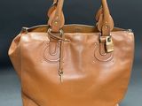 a person holding a brown purse on a black background