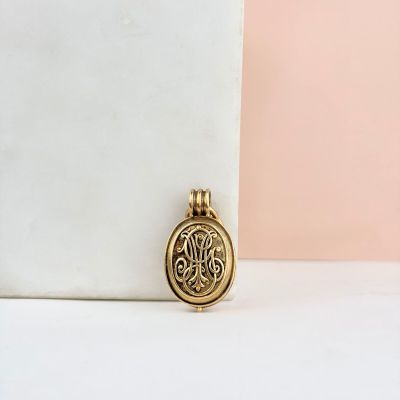 un pendentif en or orné d'un arbre, posé sur une surface blanche