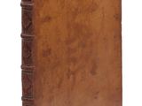 un vieux livre à la couverture brune posé sur une surface blanche