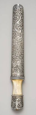 une cuillère en argent au manche sculpté, posée sur une table