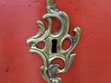 a metal keyhole on a red piece of furniture