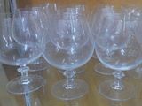 several empty wine glasses are lined up on a glass table