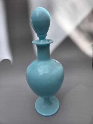 un petit vase bleu posé sur une table à côté d'un téléphone portable