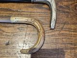 two old canes on a wooden table with a metal handle