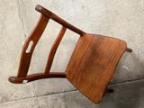 a wooden chair that is leaning up against a wall