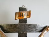 a metal cross with a rusted sign on it
