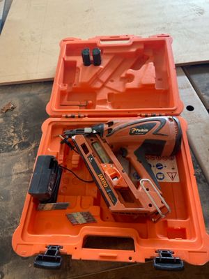 une boîte à outils orange contenant une agrafeuse et un pistolet à clous