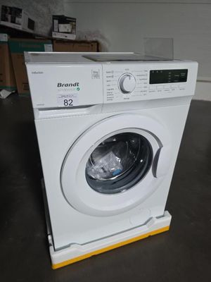 une machine à laver blanche posée par terre dans une pièce