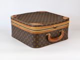 une valise marron et beige posée sur une surface blanche