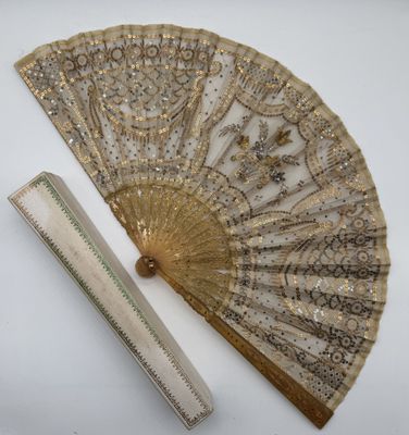 an image of a gold fan and ruler on a white surface