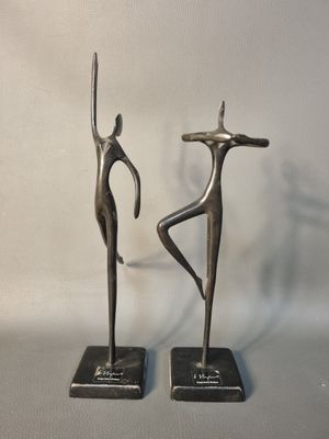 paire de sculptures métalliques représentant un homme et une femme, posées sur un socle