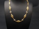 un collier en or sur un mannequin, sur fond noir