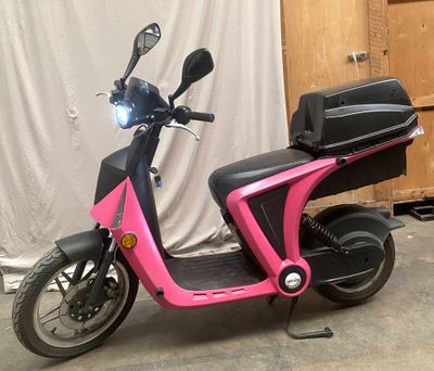 a pink scooter that is parked in a garage