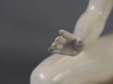 a white statue of a man sitting on a chair