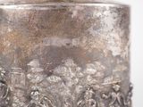 a silver vase sitting on a table with a bird perched on top of it