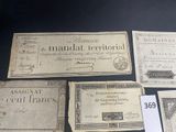 several old paper money bills are on display on a table