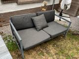 a couch that has two pillows on it in the yard